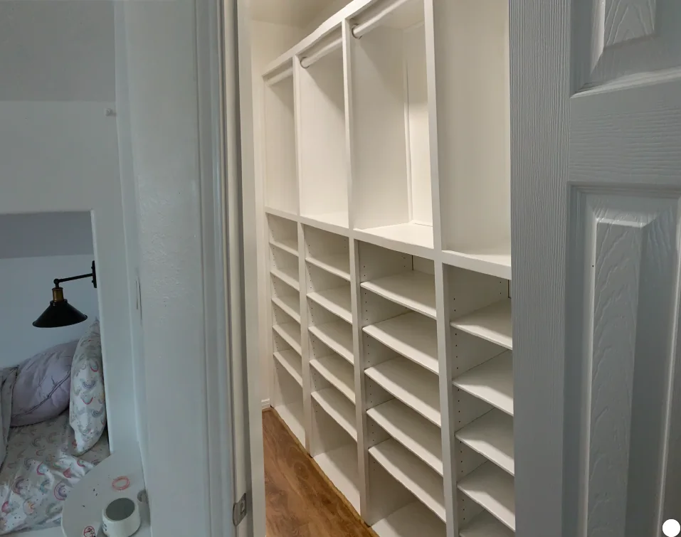 White shared children’s closet with built-in shelves, hanging spaces, and drawers.