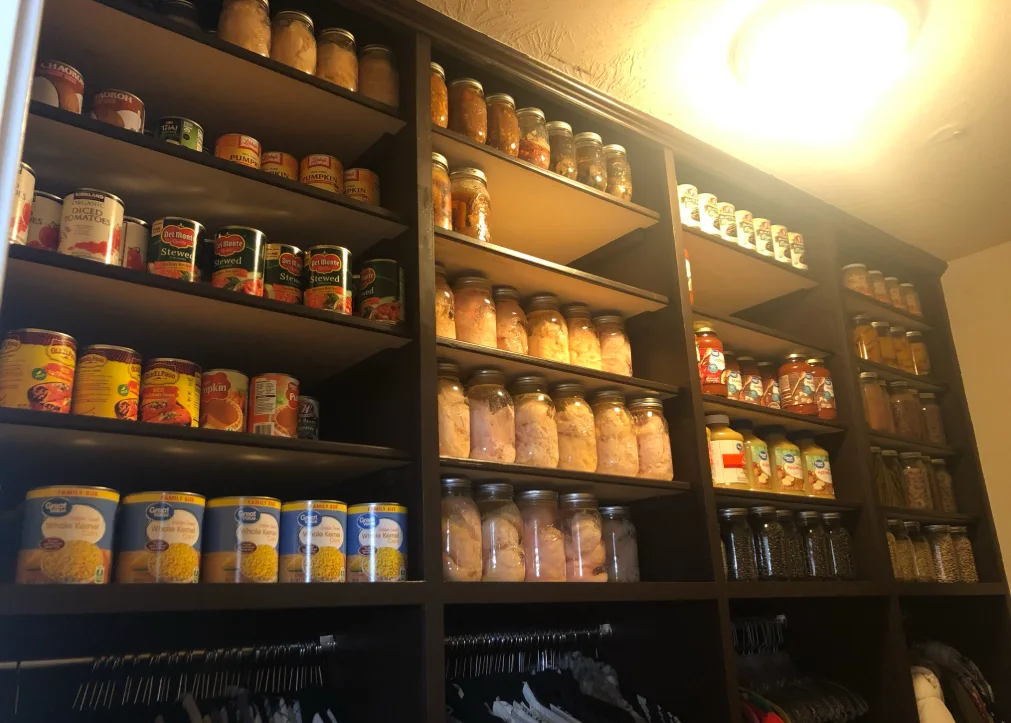 Dark wood food-storage pantry filled with organized jars, cans, and dry goods.