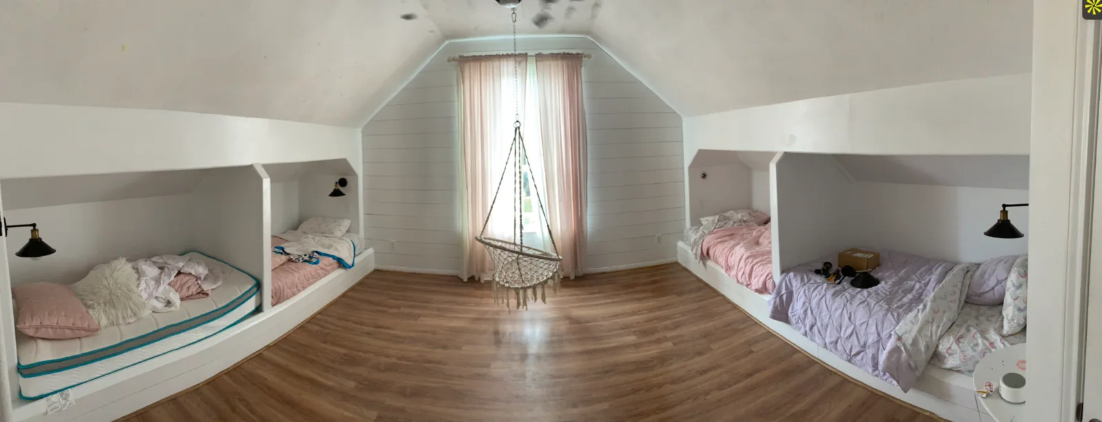 Finished children’s room with shiplap walls, paired built-in beds, reading lights, and wood flooring.